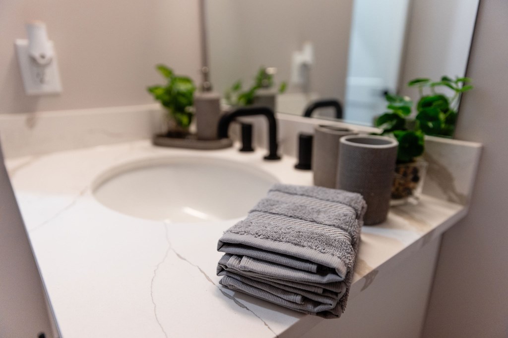 A stack of towels sits on a sink in a bathroom.