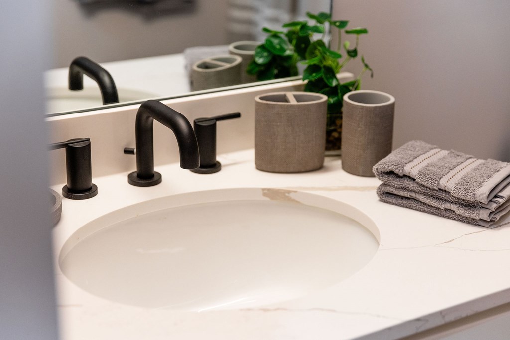 A white sink with a black faucet and towels.