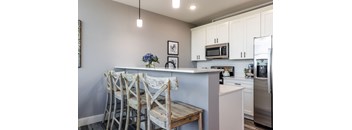 A kitchen with a white counter and bar stools.