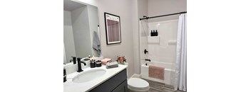 A white sink with a black faucet and a white toilet in a bathroom.