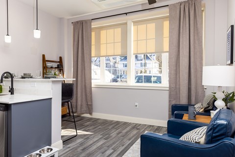 A living room with a blue couch and a kitchen area with a sink.