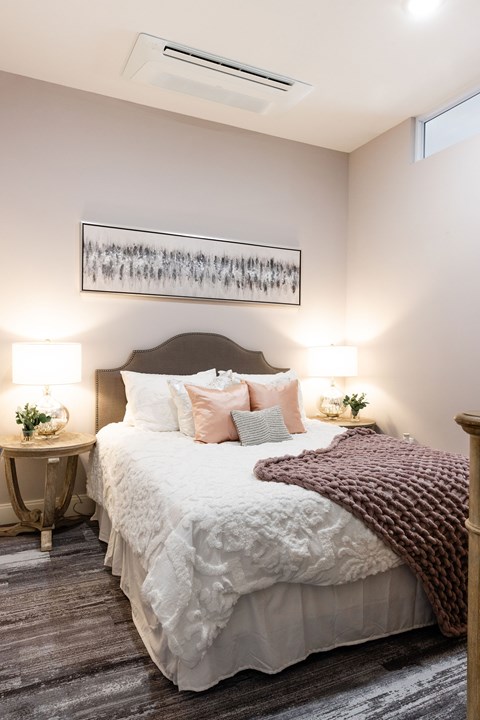 A bedroom with a large bed and a painting above it.