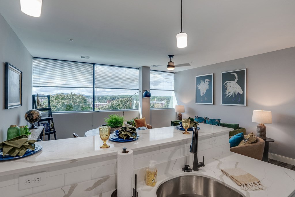 an open kitchen and living room with a large window and a sink