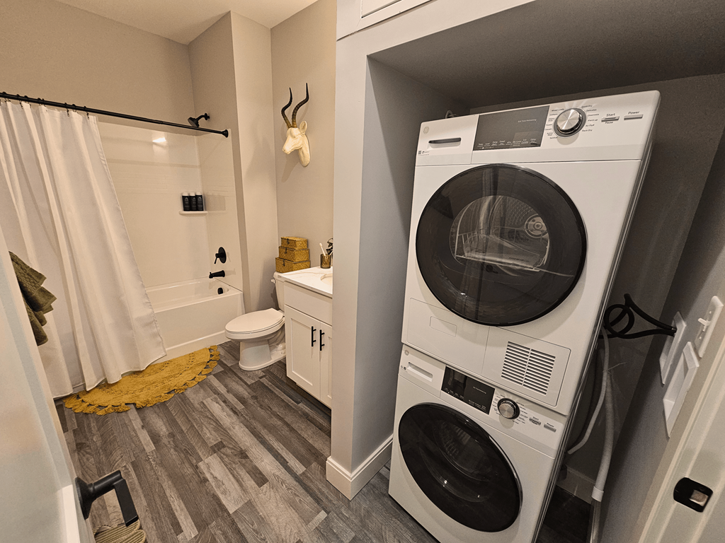 a washer and dryer in a bathroom with a shower and a toilet