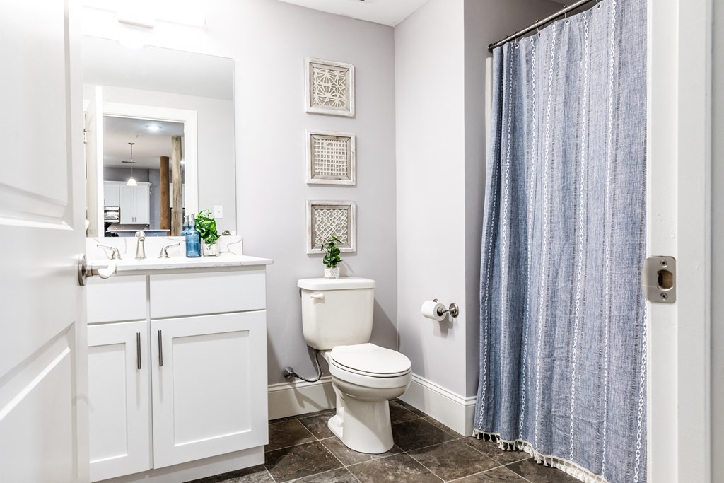 a bathroom with white cabinets and a blue shower curtain