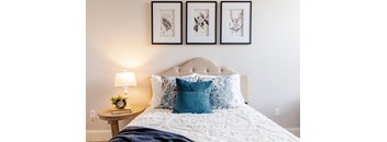 a bedroom with a bed with a white comforter and blue pillows