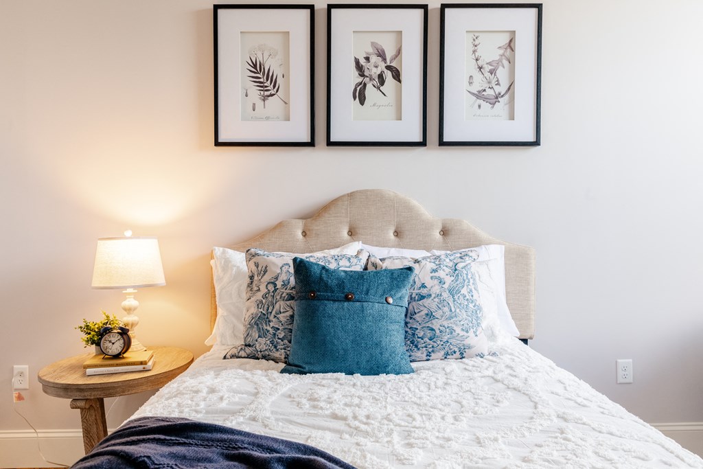 a bedroom with a bed with a white comforter and blue pillows