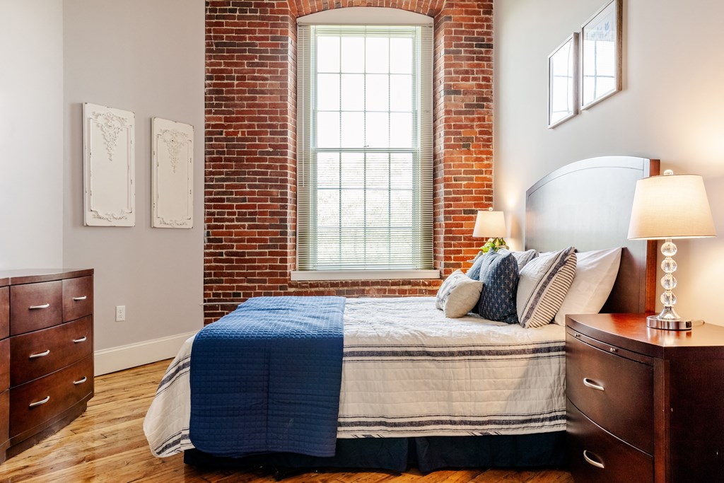 a bedroom with a bed and dresser in front of a window