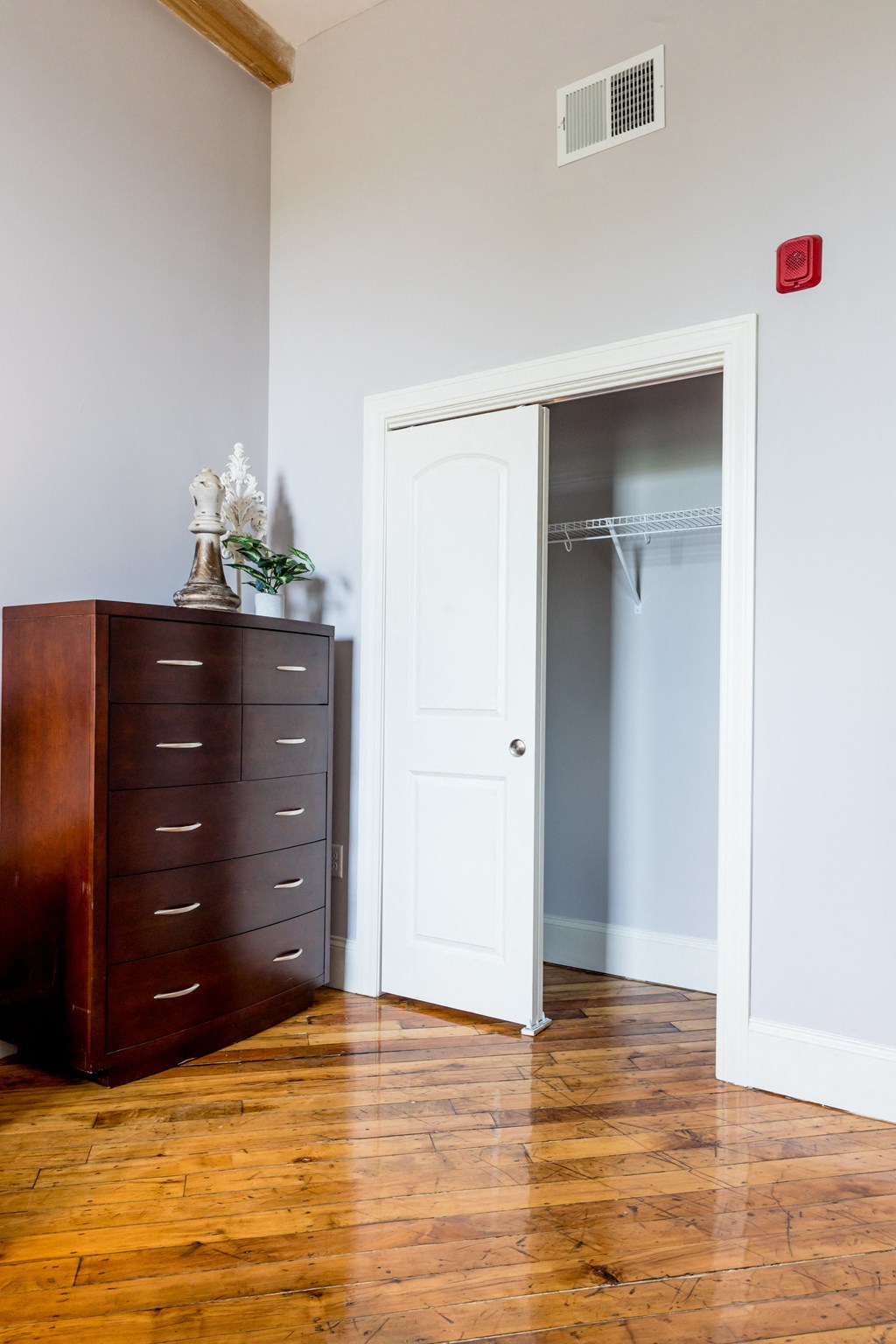 a bedroom with a dresser and closet with an open door