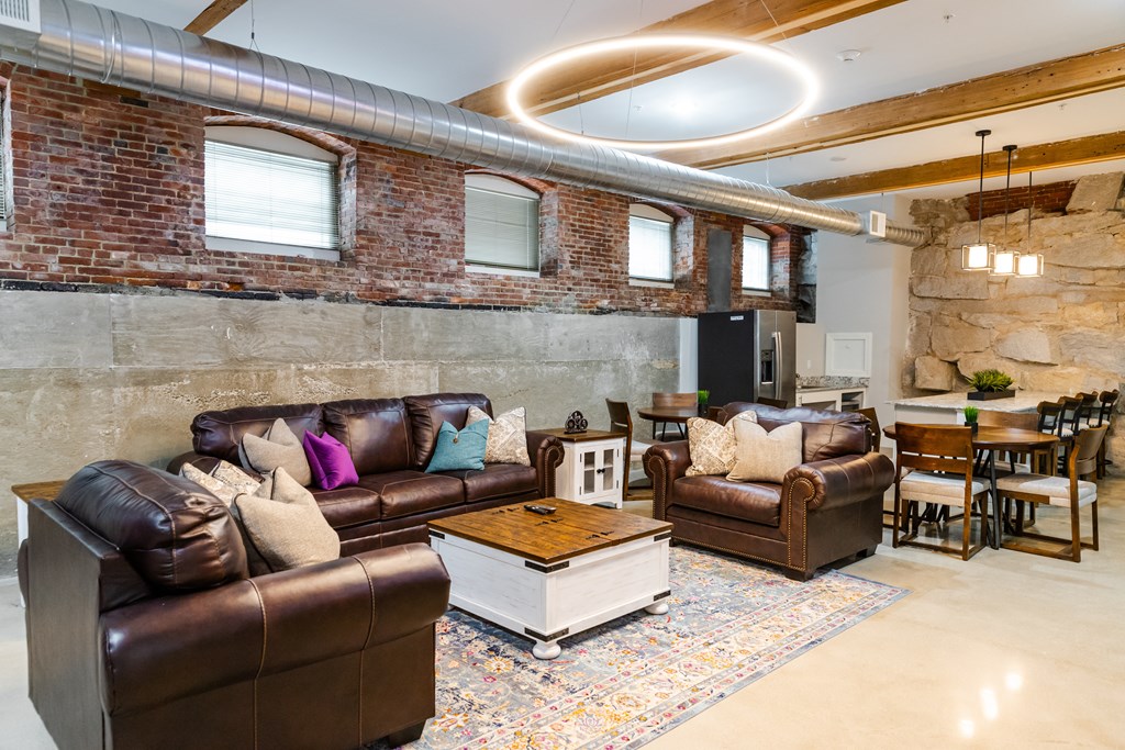 a living room with leather furniture and a brick wall