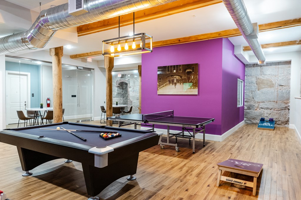 a game room with two pool tables and a purple wall