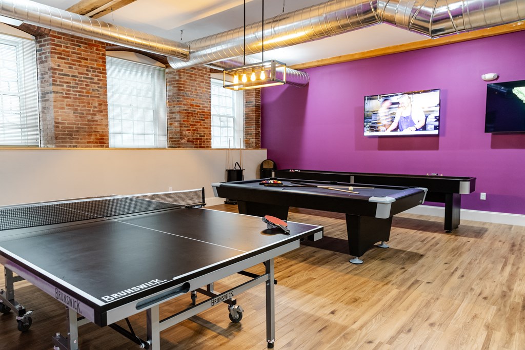 a game room with two ping pong tables and a tv