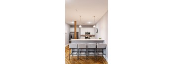 a kitchen with white cabinets and a large island with stools