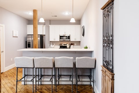 a kitchen with white cabinets and a bar with stools