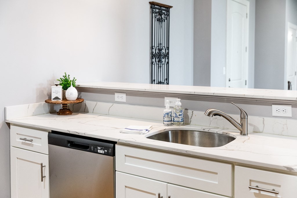 a kitchen with white cabinets and a stainless steel dishwasher