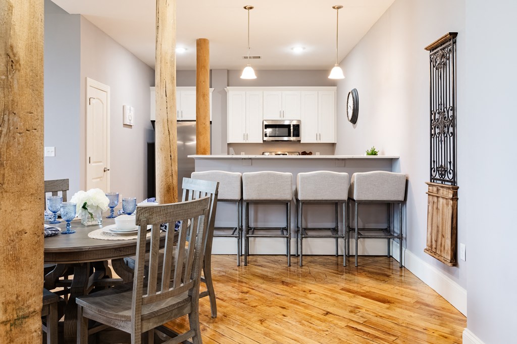 a dining area with a table and chairs and a kitchen in the background