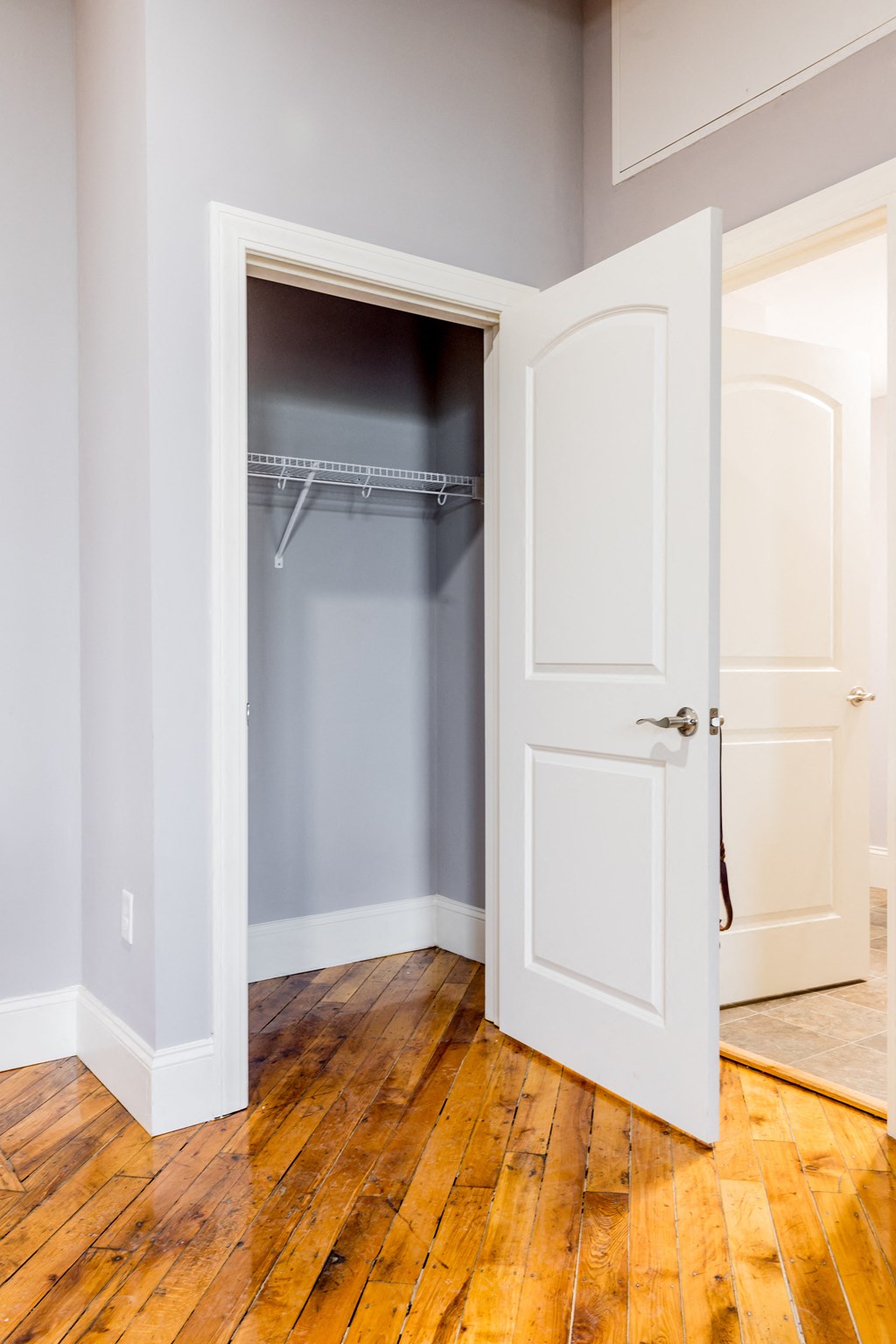 a walk in closet with a white door and a wooden floor