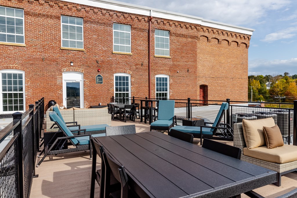 a patio with a table and chairs in front of a brick building