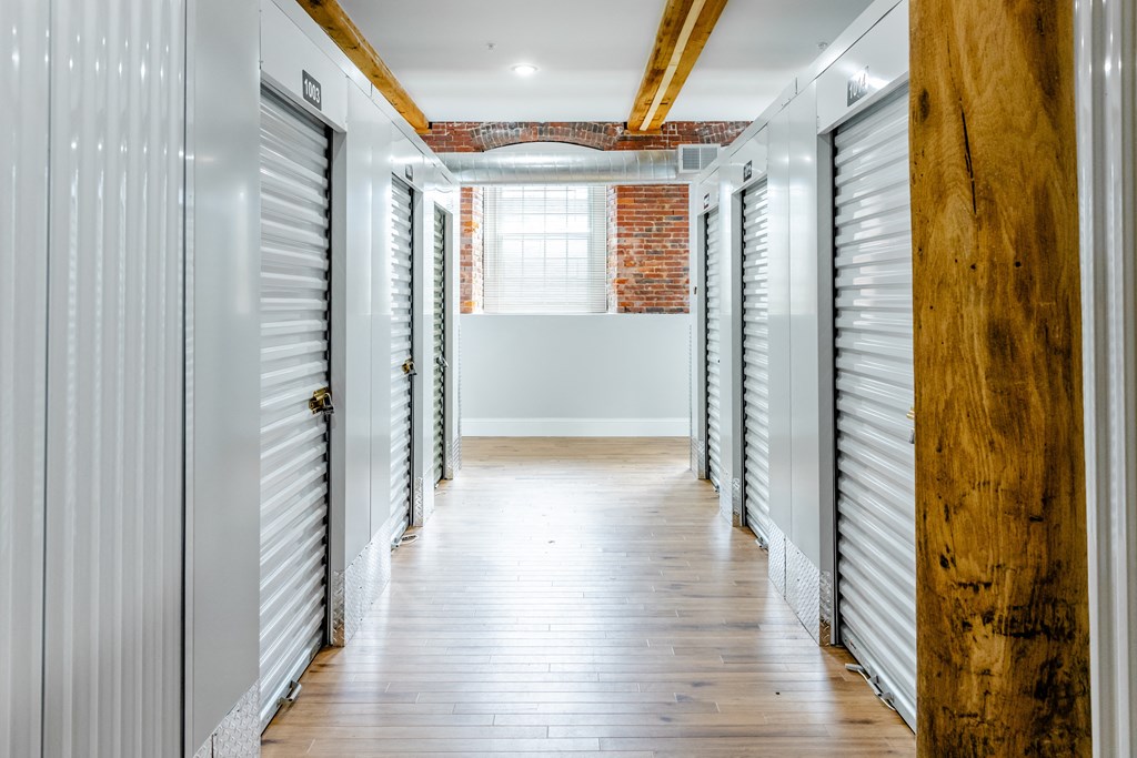 a hallway with white shutters and wood floors and a window