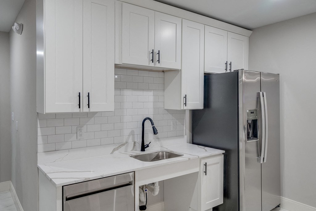 a kitchen with white cabinets and a stainless steel refrigerator
