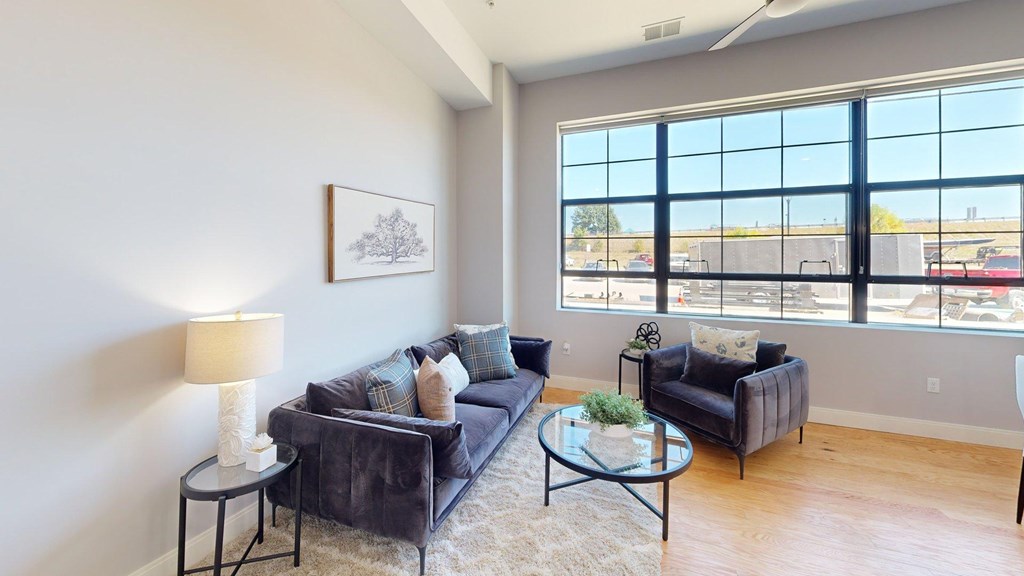A living room with a couch, a chair, a table, and a painting on the wall.