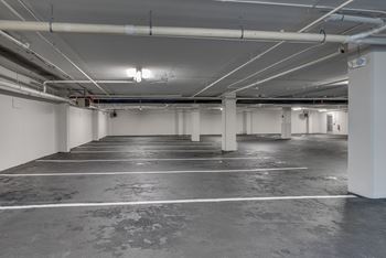A spacious, empty parking garage with concrete floors and white walls.