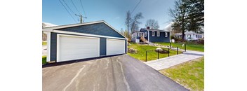 A blue house with a white garage door is in front of a grassy area.