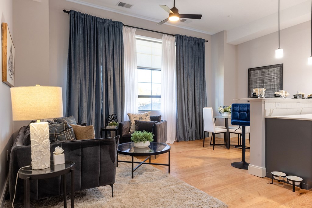 A living room with a grey couch, a coffee table, a fireplace, and a ceiling fan.