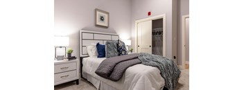 A bedroom with a bed, nightstand, and a picture on the wall.