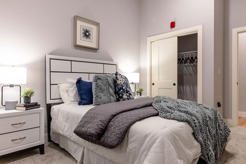 A bedroom with a bed, nightstand, and a picture on the wall.