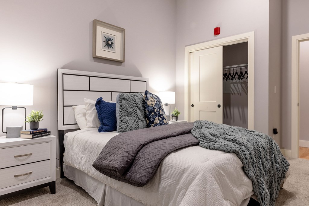 A bedroom with a bed, nightstand, and a picture on the wall.