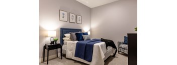 A bedroom with a bed, a nightstand, and a chair.