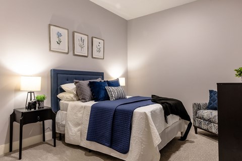 A bedroom with a bed, a nightstand, and a chair.