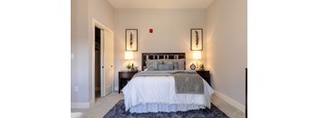 A bedroom with a large bed and two wall lamps.