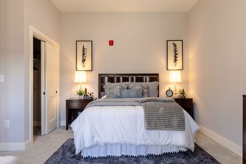 A bedroom with a large bed and two wall lamps.