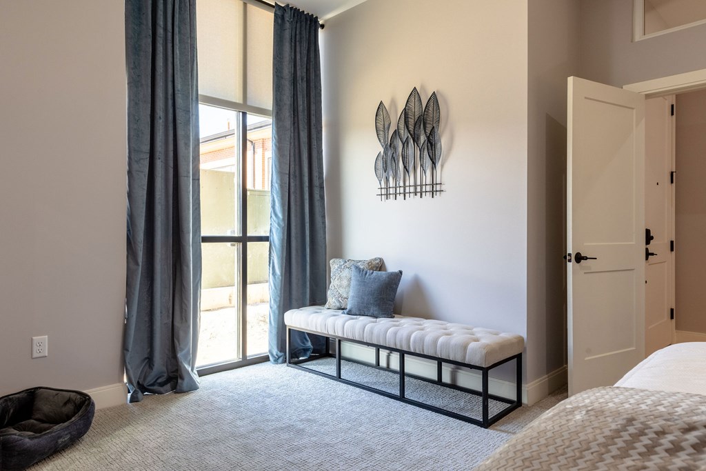 A bedroom with a bed, a bench, and a wall art.