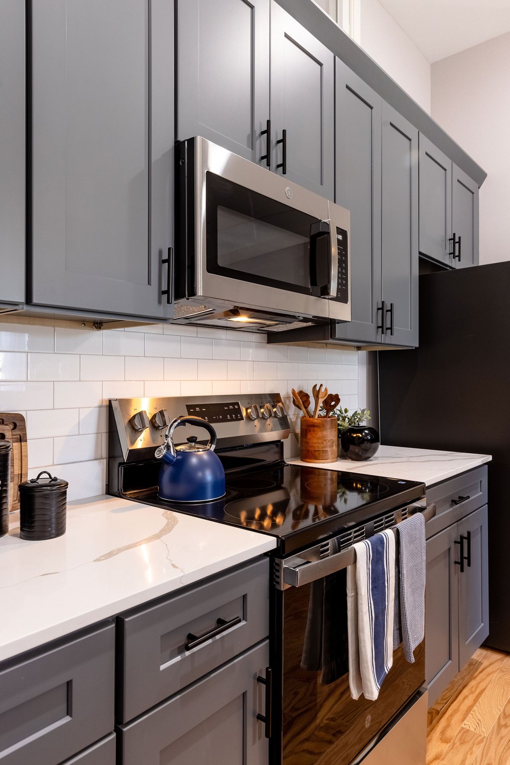 A modern kitchen with dark grey cabinets and a white countertop.
