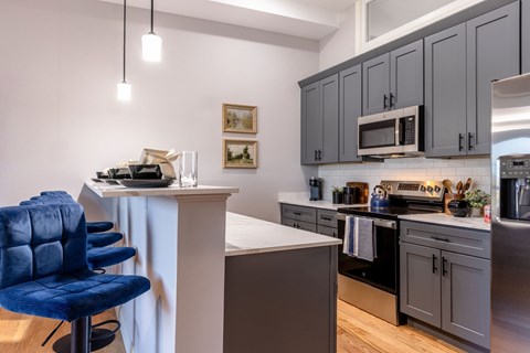 A kitchen with a blue chair and grey cabinets.