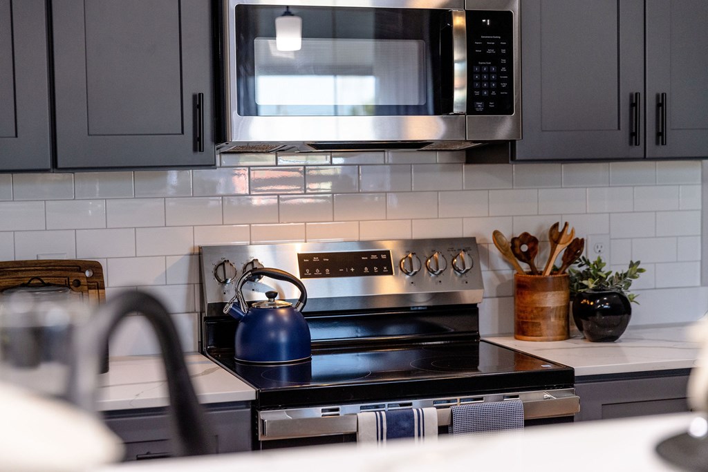 A modern kitchen with a black stove top and a black microwave above it.