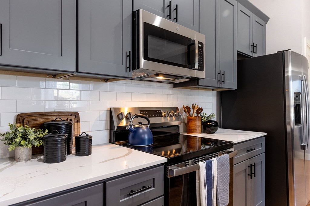 A kitchen with a black stove top oven and a black microwave above it.