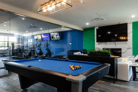 A pool table is in the middle of a room with a blue wall.