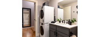 A white washing machine and dryer stacked on top of each other in a laundry room.
