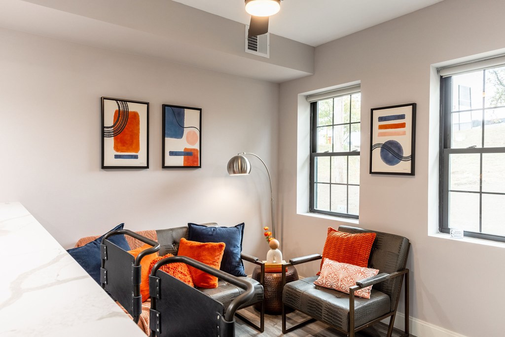 A living room with a grey couch and a white bed.