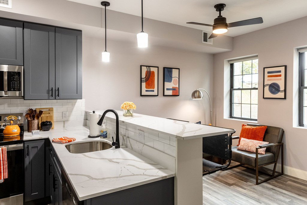 A modern kitchen with a marble countertop and black cabinets.