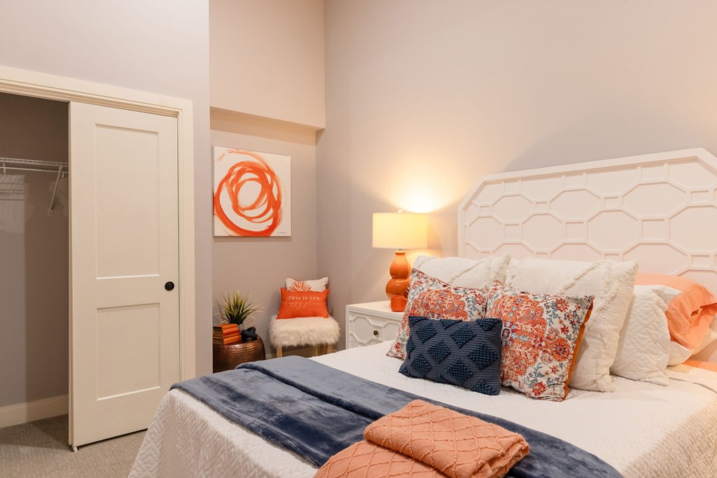 A bedroom with a bed, pillows, and a lamp.