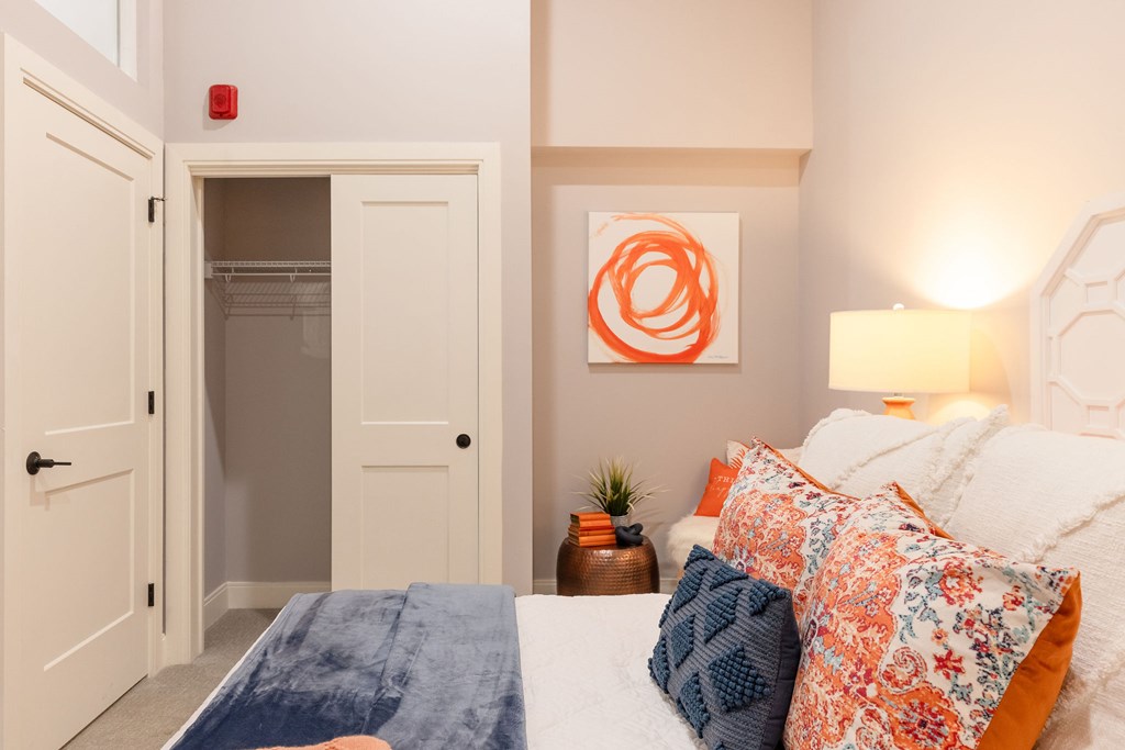 A bedroom with a bed, pillows, and a painting on the wall.