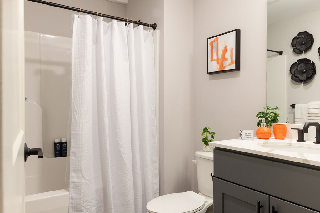 A white shower curtain hangs over a glass shower door in a bathroom.