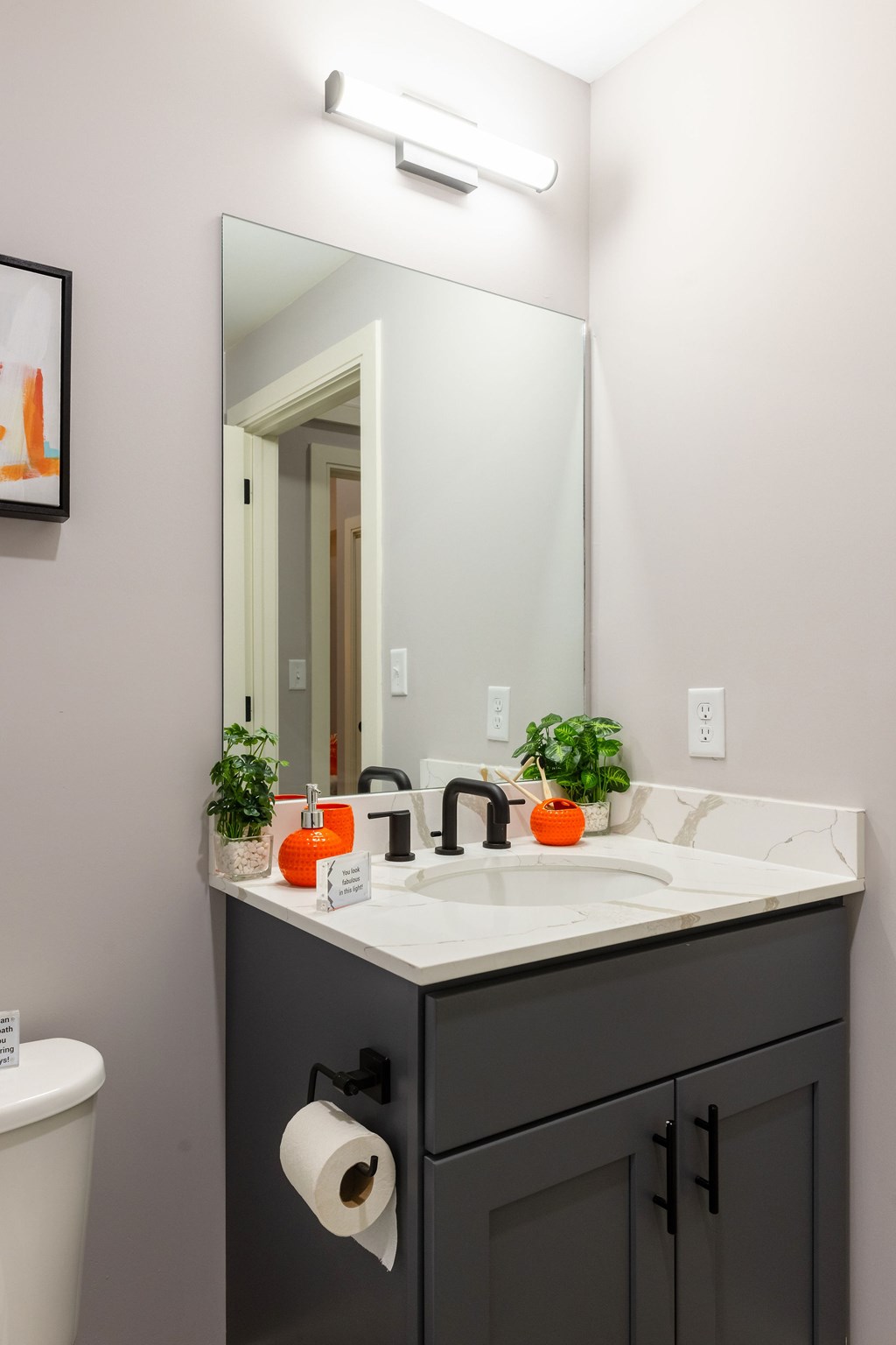 A bathroom with a sink, toilet, and a mirror.