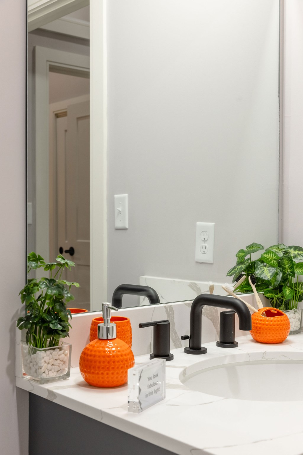 A bathroom sink with a black faucet and an orange soap holder.