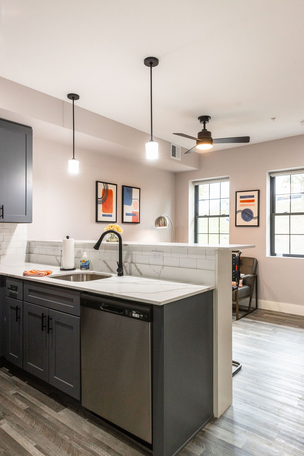 A kitchen with a white sink and black cabinets.